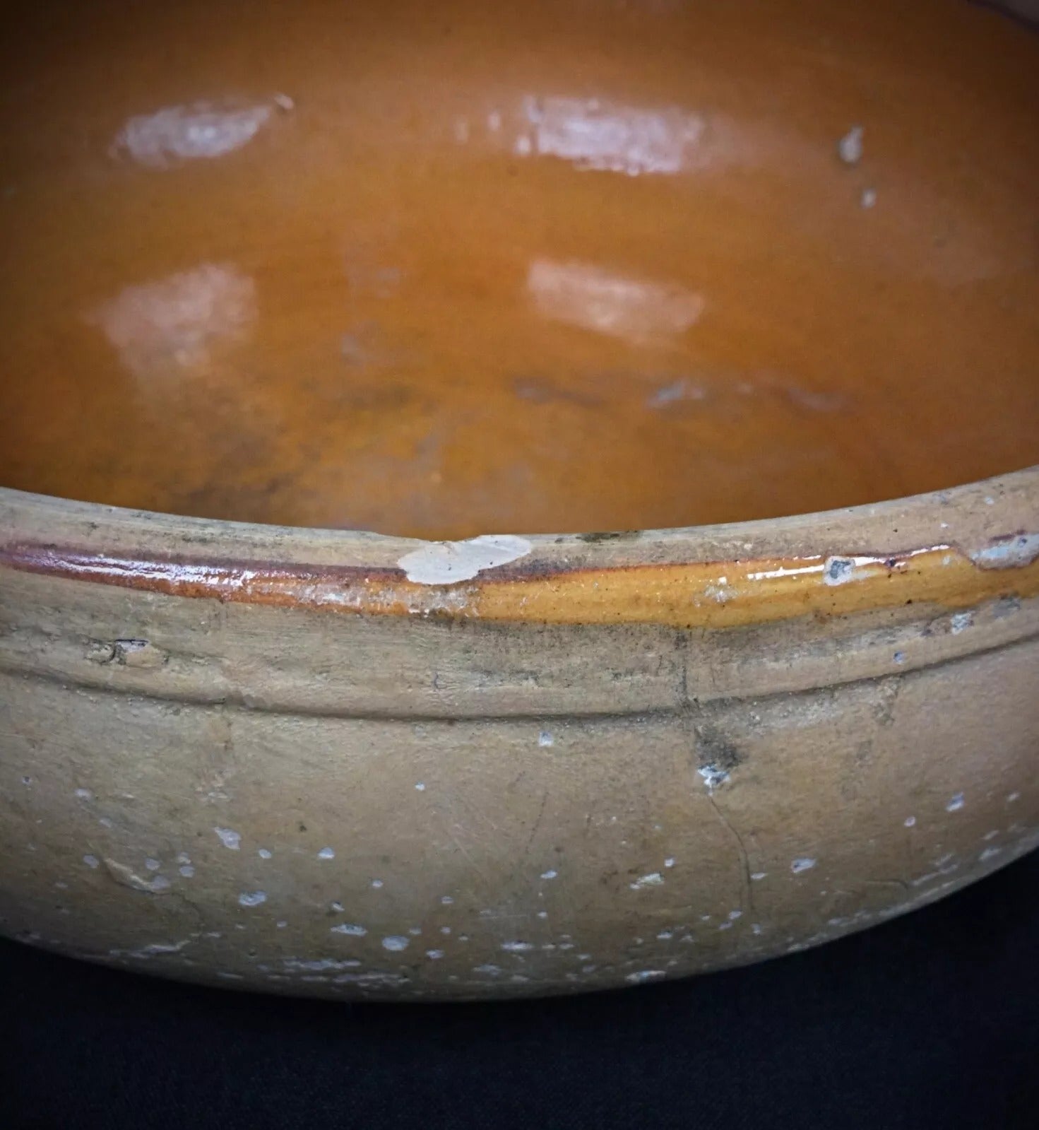 Aged terracotta surface with warm earthy color and patina on a signed French pottery pan from the 20th century