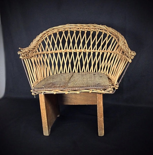 Early 1900s child-sized chair with rustic wood frame and woven wicker seat on display

