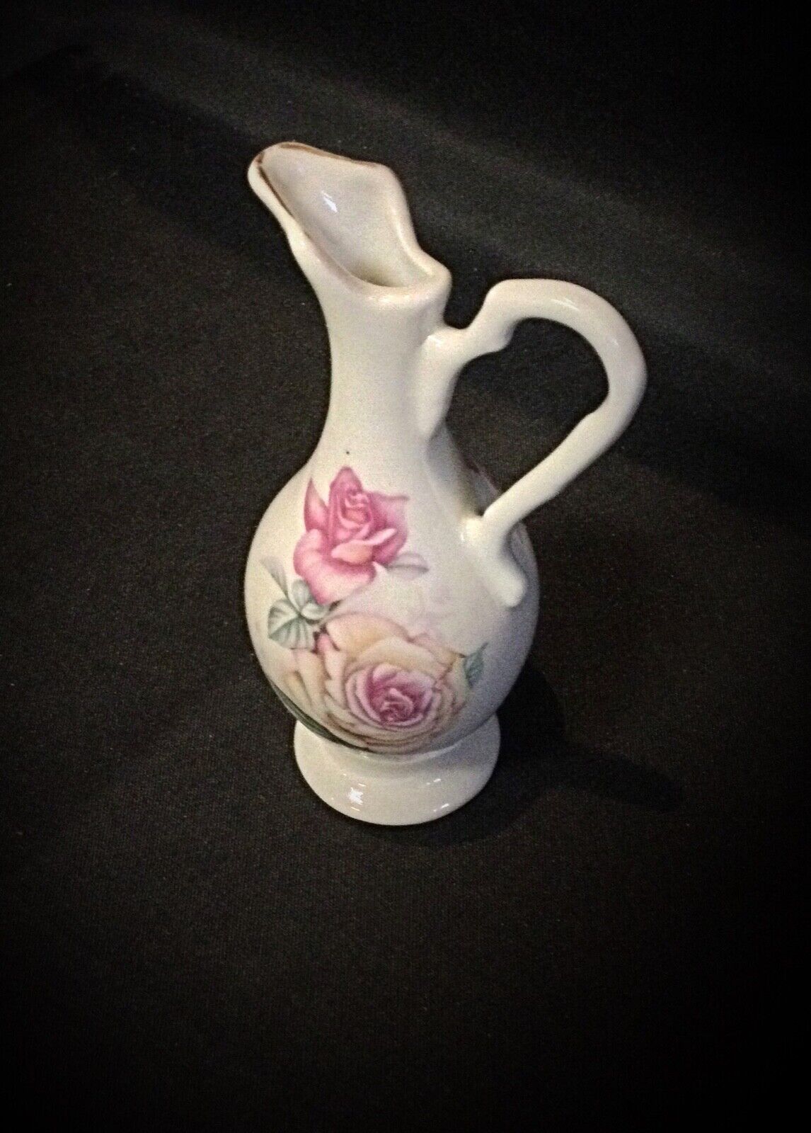 Side view of a small porcelain vase with delicate handles and floral motif
