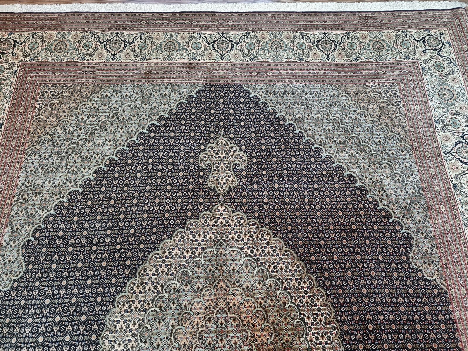 Close-up of the muted tones and variations due to age and wear on the rug