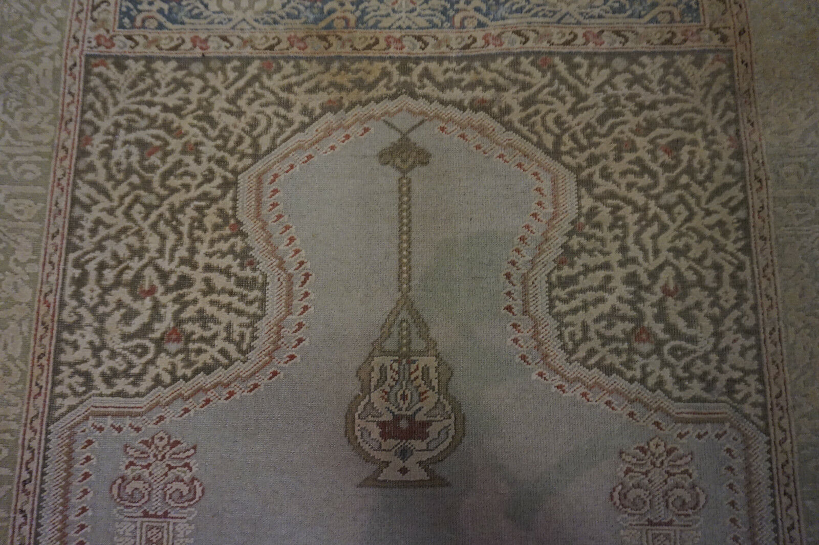 Close-up of the muted earthy tones and faded reds on the rug