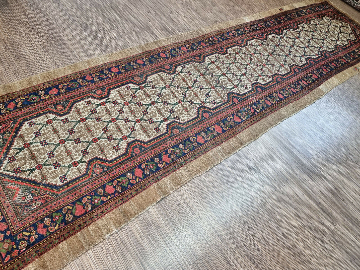 Close-up of intricate floral motifs on Handmade Antique Persian Camel Hair Runner Rug - Detailed view showcasing the intricate floral motifs adorning the border of the rug.