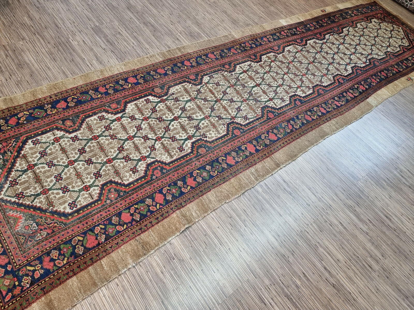 Close-up of intricate floral motifs on Handmade Antique Persian Camel Hair Runner Rug - Detailed view showcasing the intricate floral motifs adorning the border of the rug.