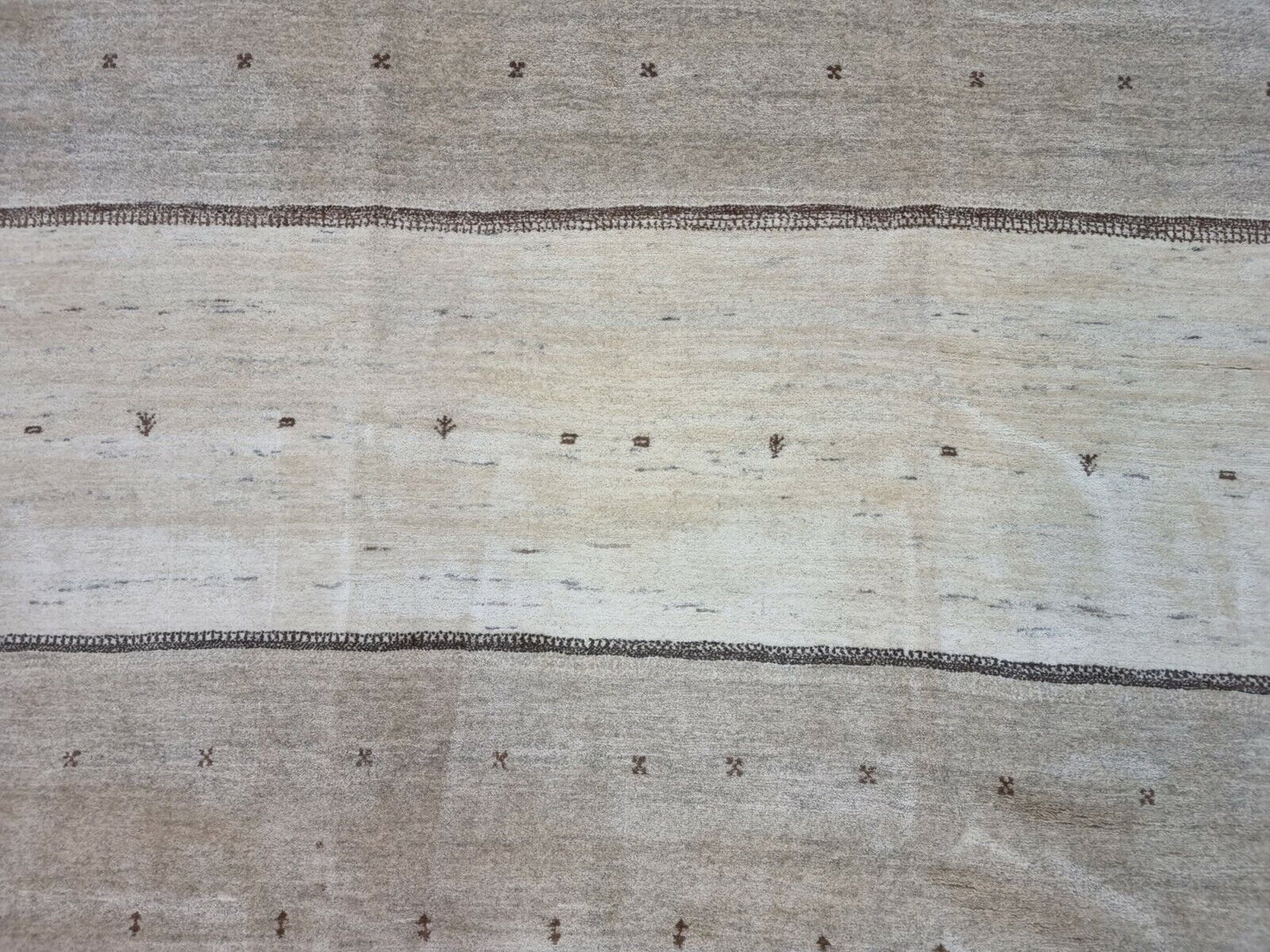 Close-up of the subtle distress and irregular dark spots on the Handmade Vintage Persian Style Gabbeh Rug