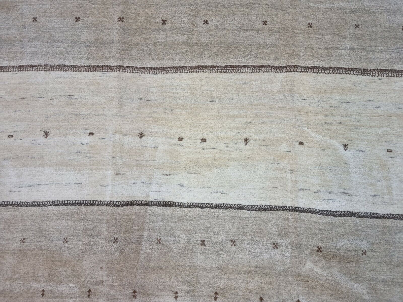 Close-up of the subtle distress and irregular dark spots on the Handmade Vintage Persian Style Gabbeh Rug