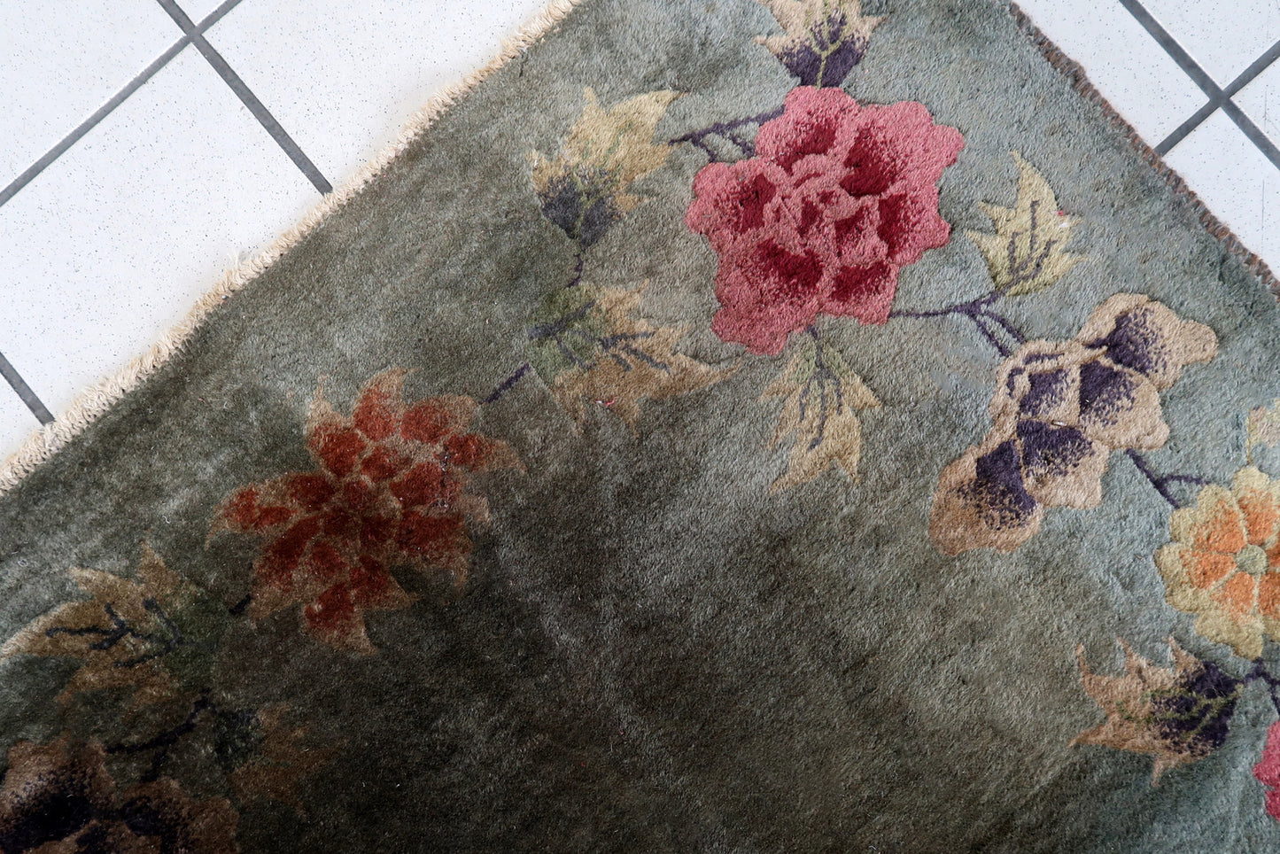 Handmade antique Art Deco Chinese rug in green color and floral design. The rug is from the end of 20th century in original condition, it has some age discolorations and signs of wear.