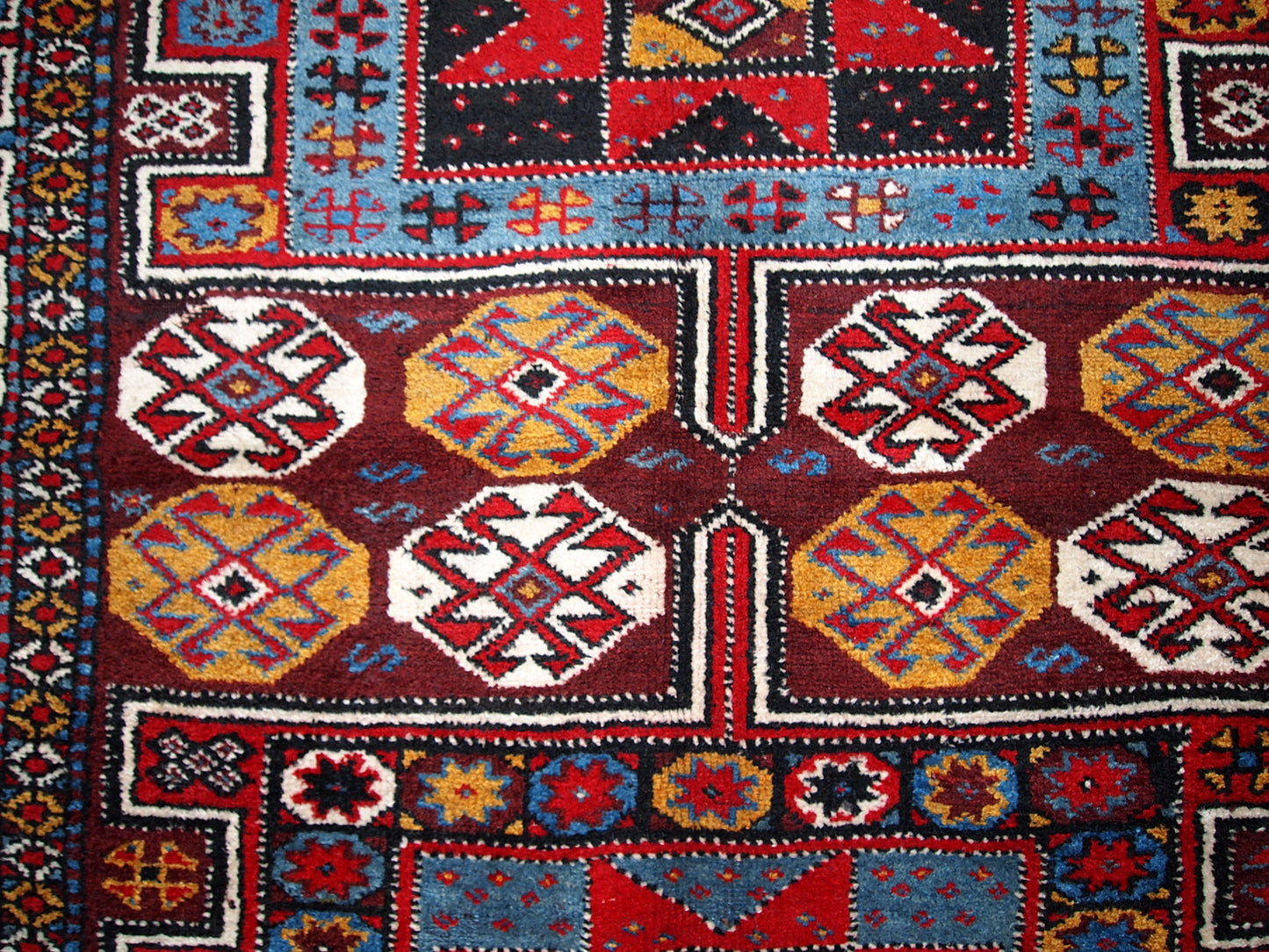 Antique Persian Kurdish rug in deep burgundy color with some golden, white and sky blue shades. This rug is in original good condition.