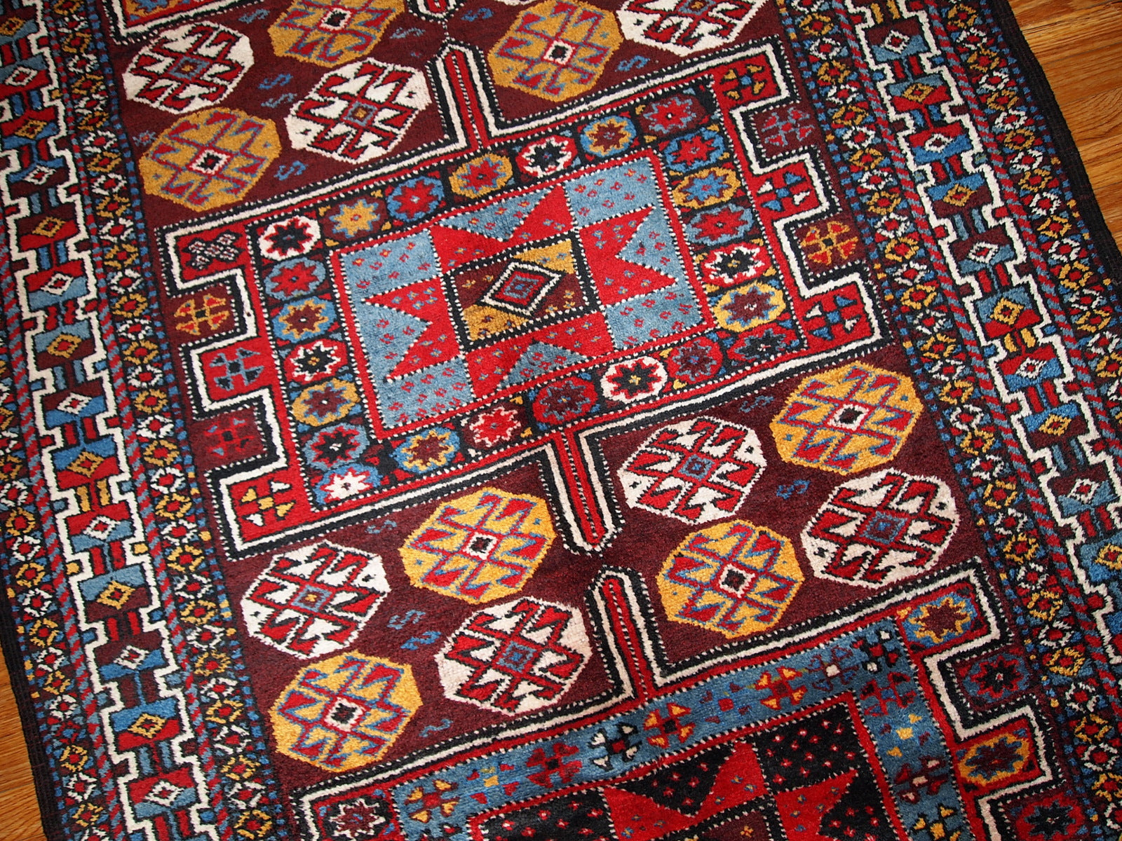 Antique Persian Kurdish rug in deep burgundy color with some golden, white and sky blue shades. This rug is in original good condition.