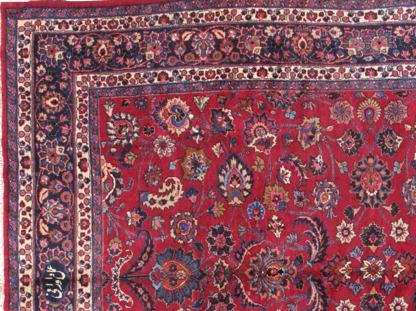 Antique Persian Mashad rug in original good condition. The field of the rug is in red shade with floral design and navy blue border. 