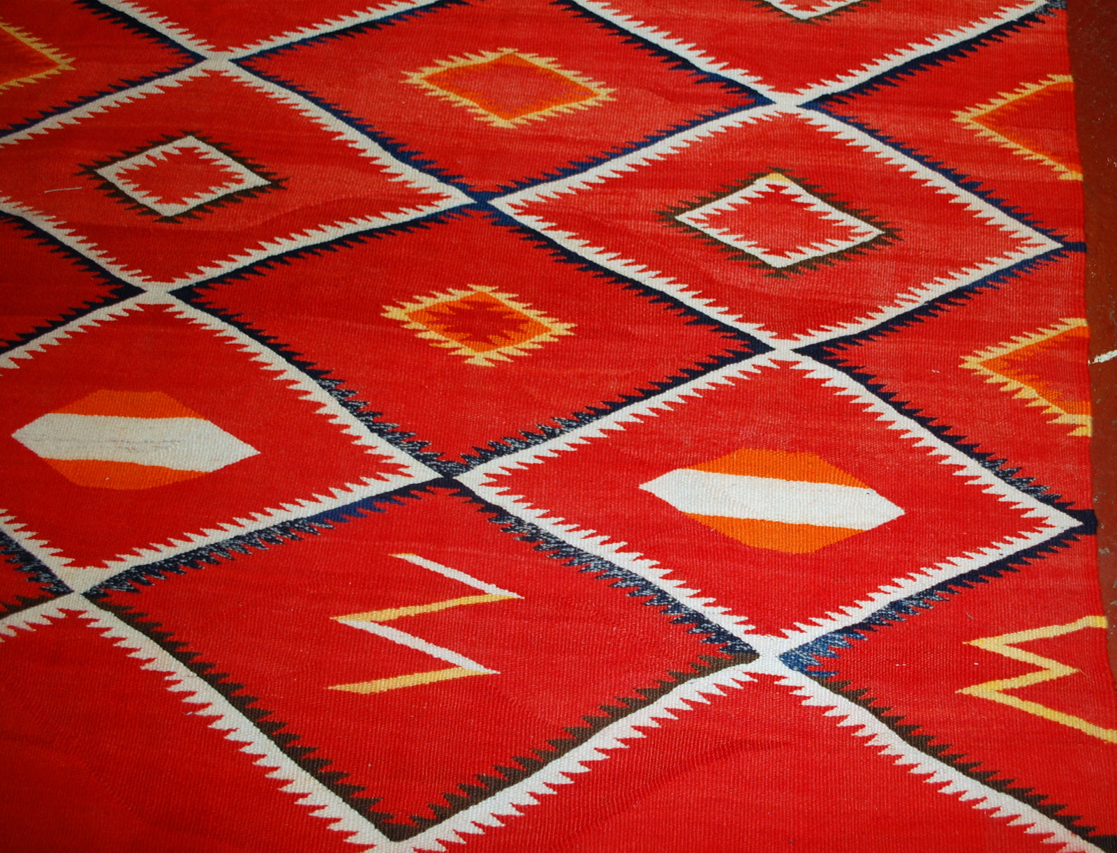 Antique hand-woven American-Indian Navajo blanket in original good condition. The blanket has been made in the end of 19th century in bright red shade. Repeating diamonds are in white and indigo shades. Smaller inner diamonds are in yellow and orange.