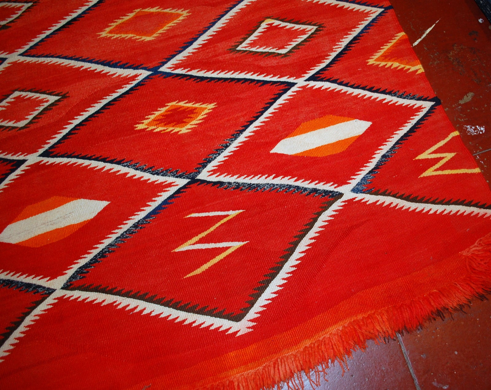 Antique hand-woven American-Indian Navajo blanket in original good condition. The blanket has been made in the end of 19th century in bright red shade. Repeating diamonds are in white and indigo shades. Smaller inner diamonds are in yellow and orange.