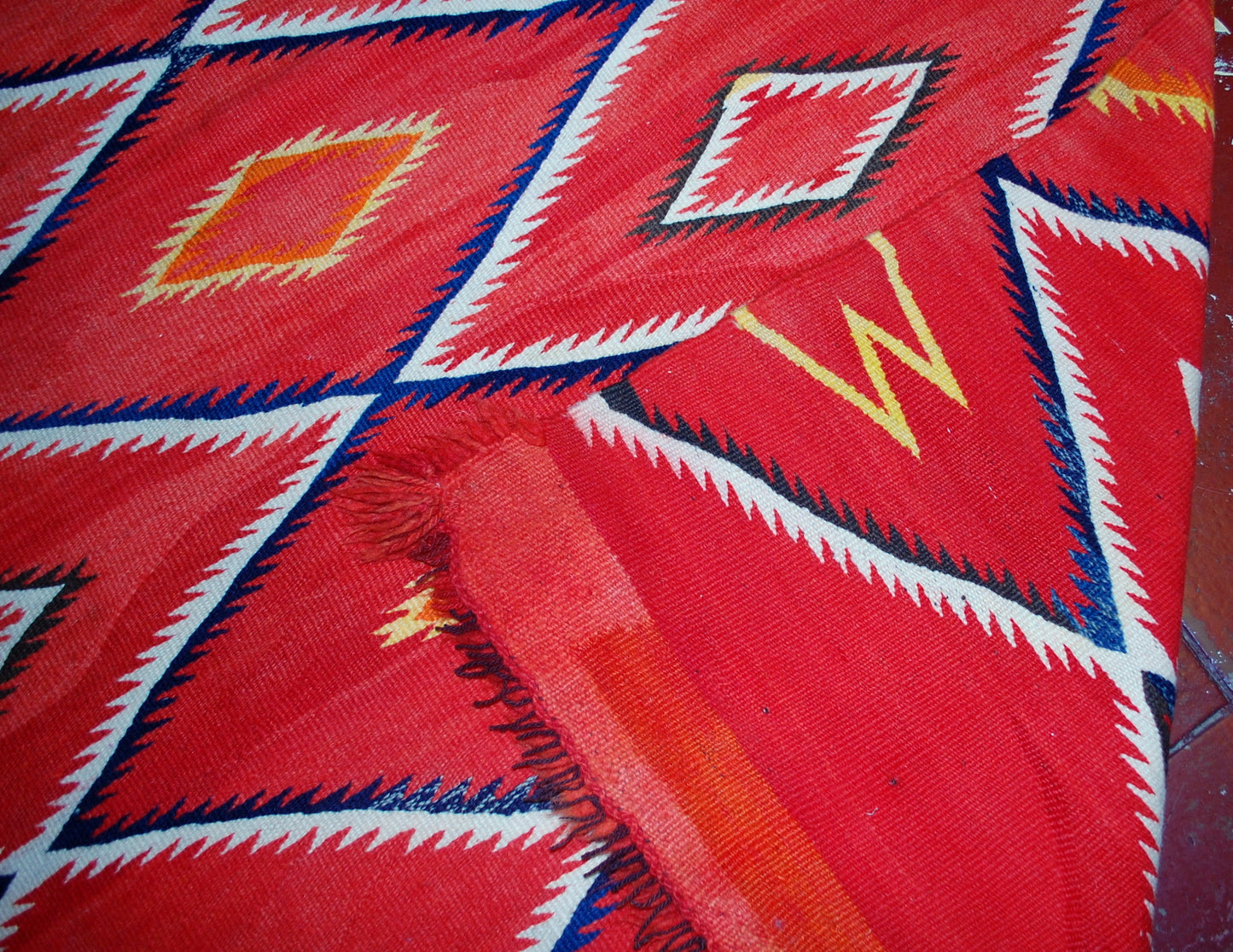 Antique hand-woven American-Indian Navajo blanket in original good condition. The blanket has been made in the end of 19th century in bright red shade. Repeating diamonds are in white and indigo shades. Smaller inner diamonds are in yellow and orange.