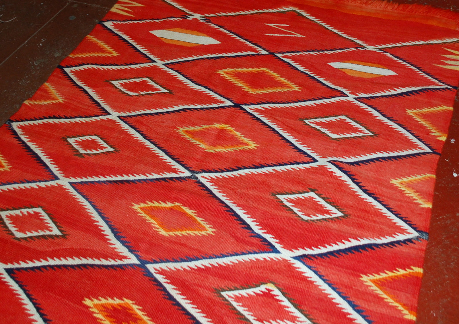 Antique hand-woven American-Indian Navajo blanket in original good condition. The blanket has been made in the end of 19th century in bright red shade. Repeating diamonds are in white and indigo shades. Smaller inner diamonds are in yellow and orange.
