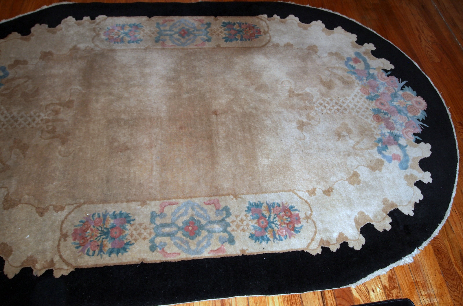 Handmade antique oval Art Deco Chinese rug in light brown shade with black border. The rug is in original good condition.