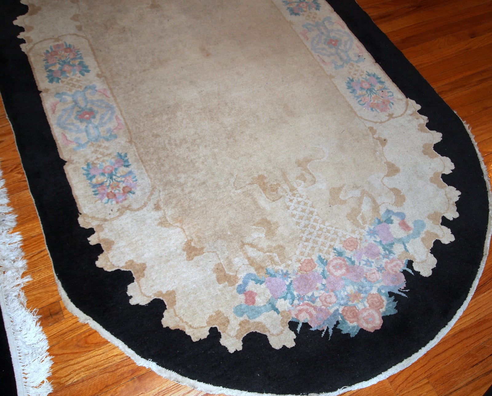 Handmade antique oval Art Deco Chinese rug in light brown shade with black border. The rug is in original good condition.