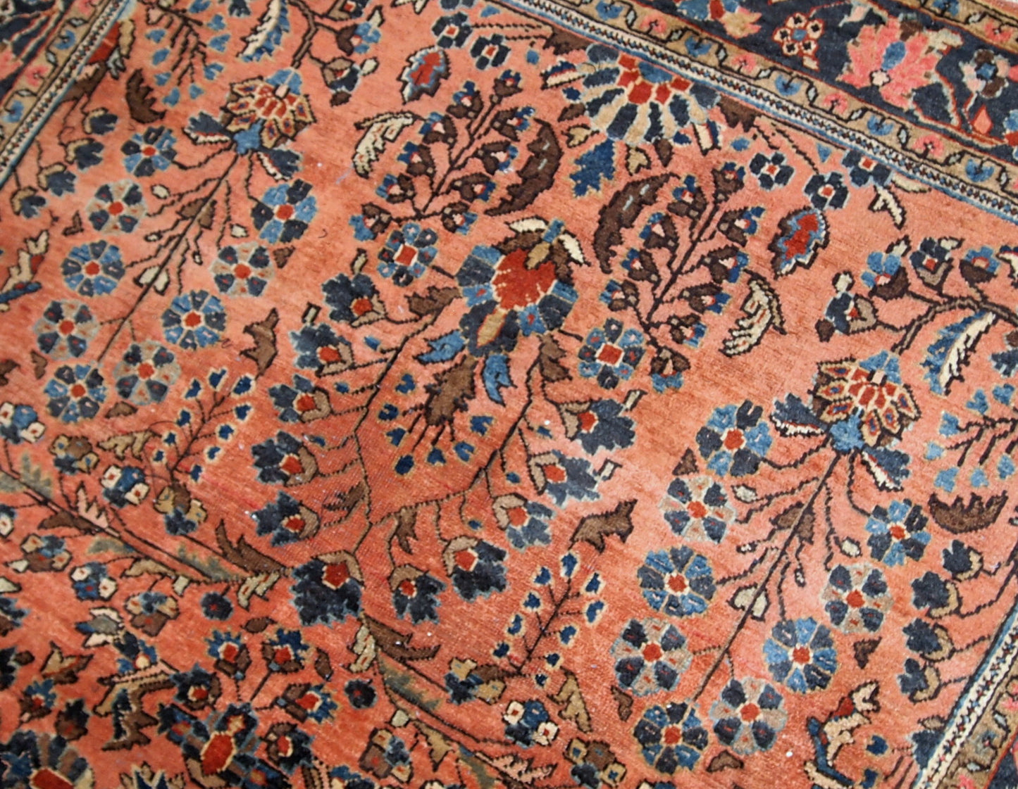 Handmade antique Sarouk rug in salmon shade. The rug is in original good condition from the beginning of 20th century.
