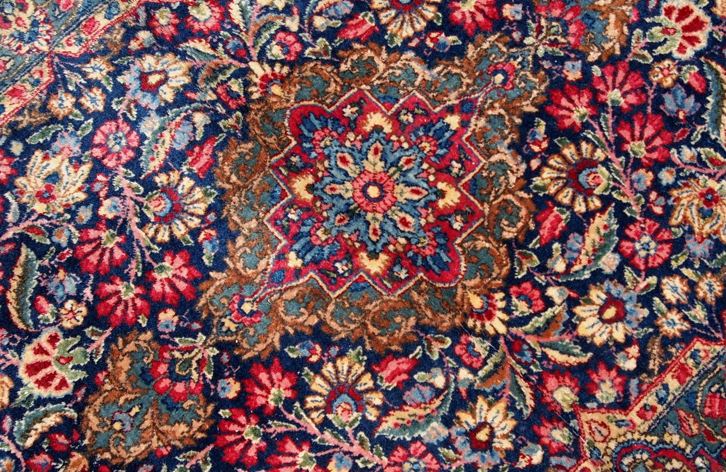 Handmade antique Kerman rug from the beginning of 20th century. The rug is in original good condition made in colorful shades and floral design.