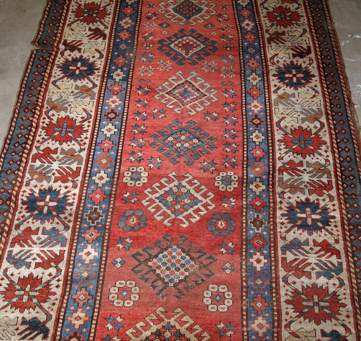 Handmade antique Caucasian Kazak rug in red and beige shades. The rug is from the end of 19th century in original condition, it has some low pile, a little cut on one side.