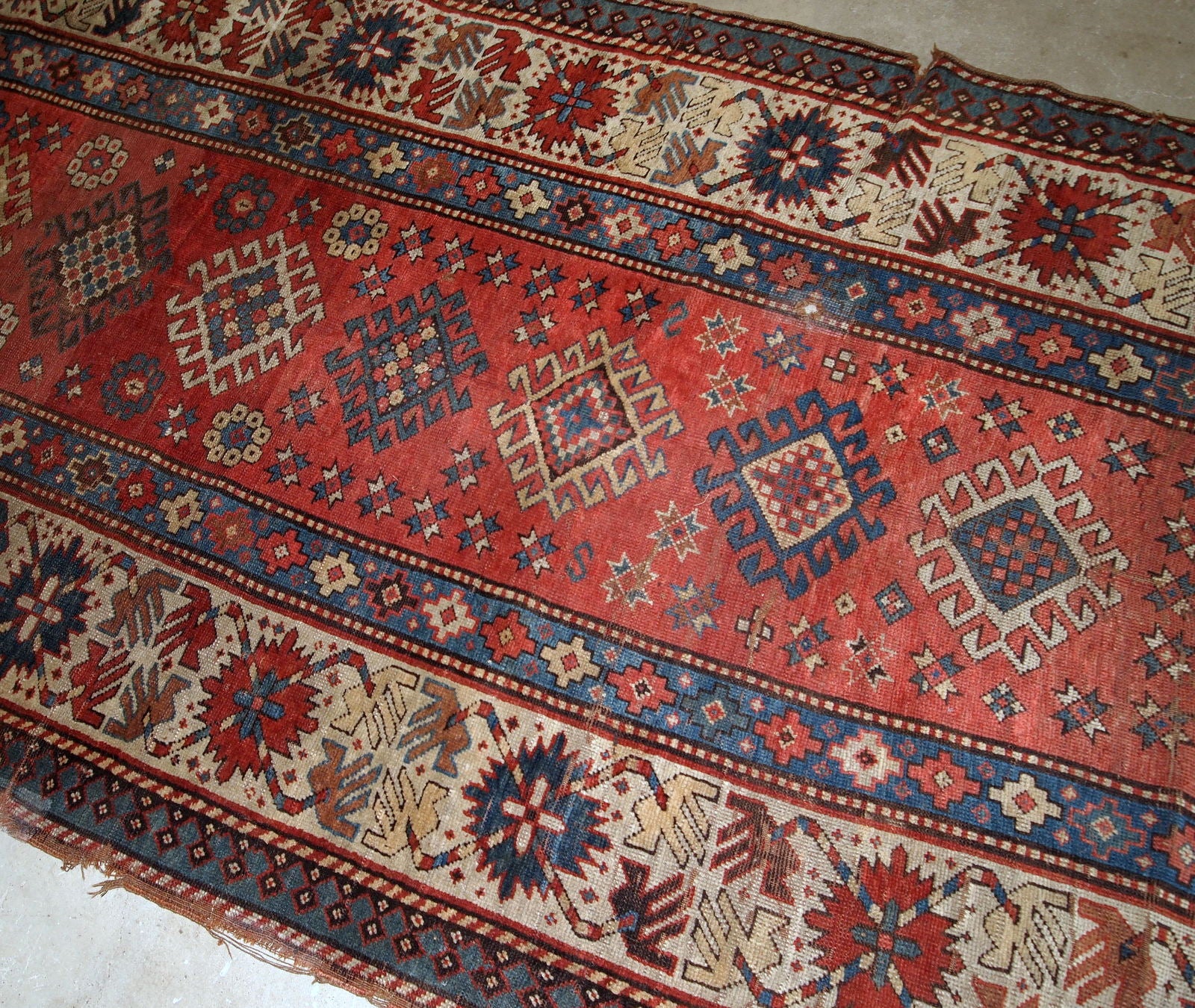 Handmade antique Caucasian Kazak rug in red and beige shades. The rug is from the end of 19th century in original condition, it has some low pile, a little cut on one side.