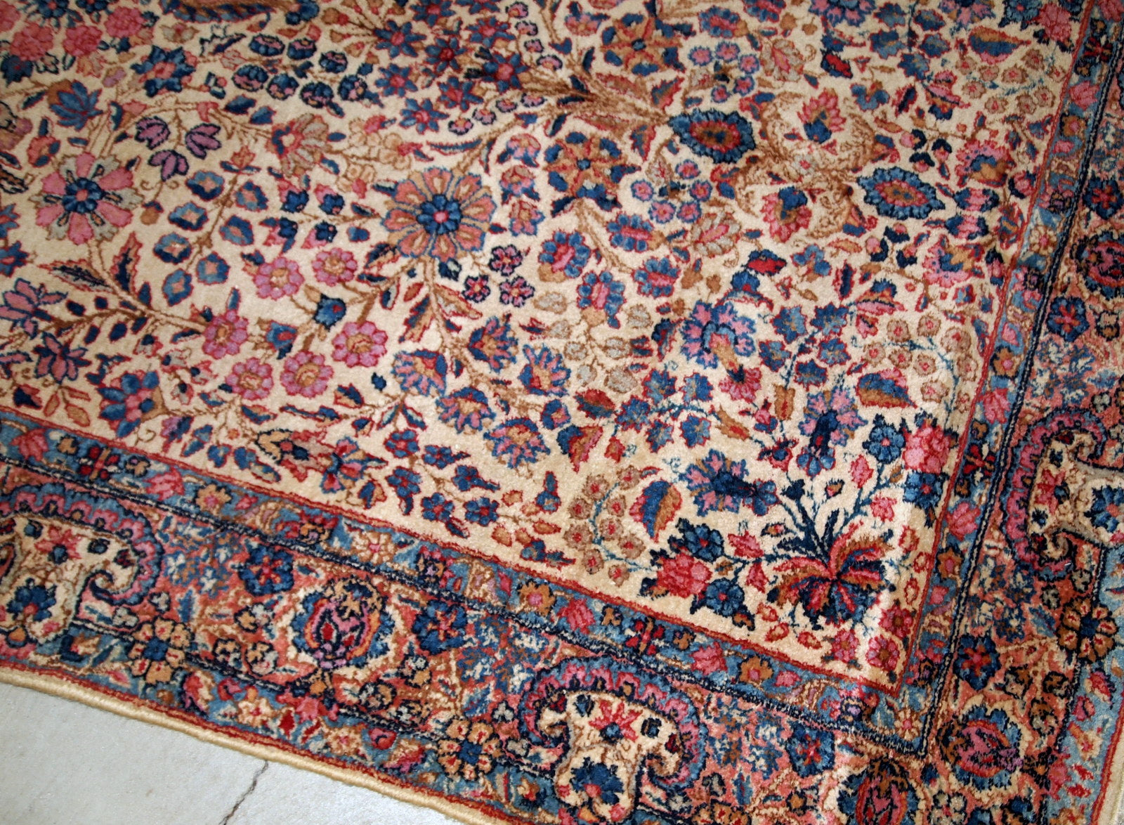 Hand-woven antique Kerman rug in original good condition, from the beginning of 20th century. The rug is in light shades and busy floral design.
