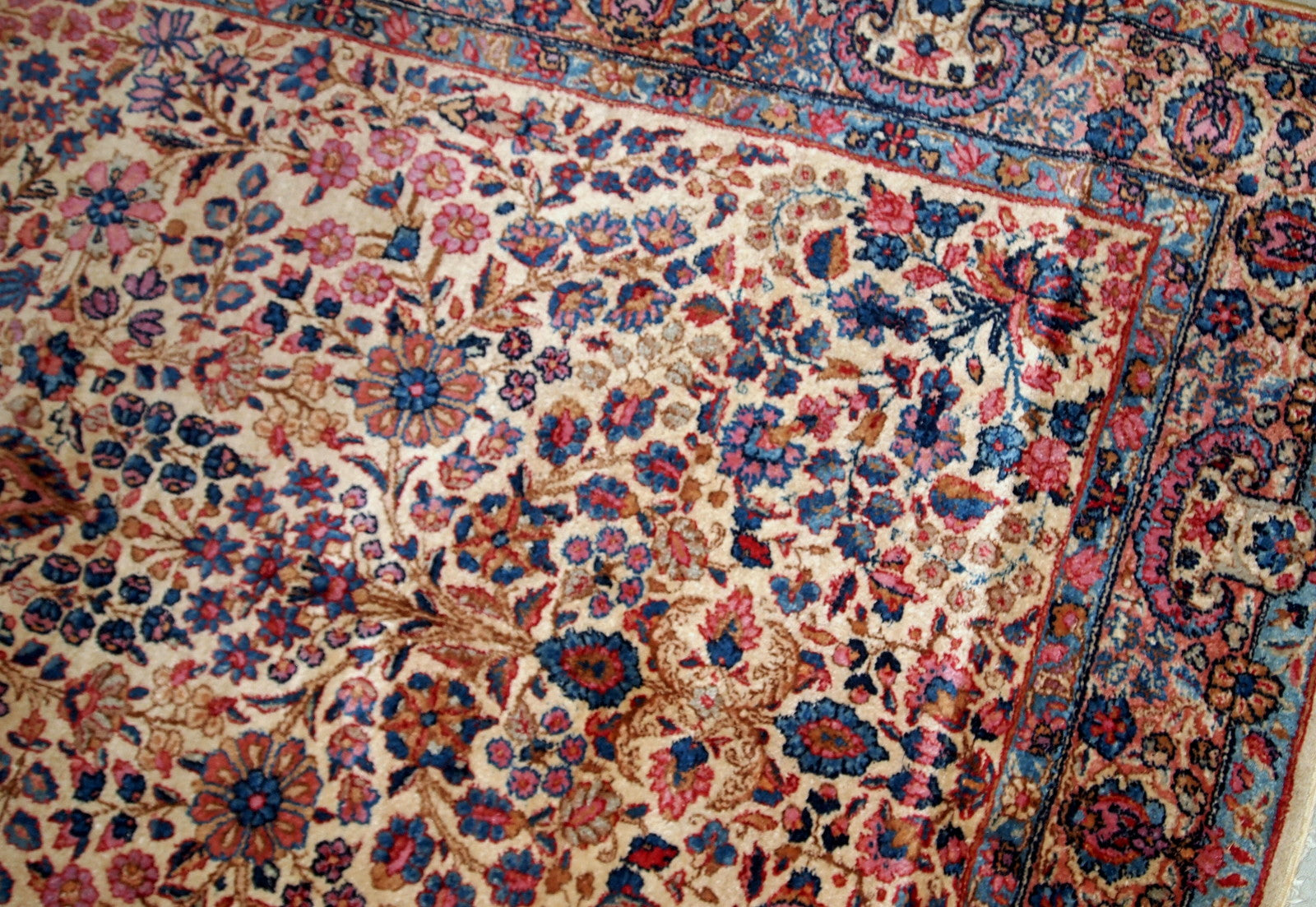 Hand-woven antique Kerman rug in original good condition, from the beginning of 20th century. The rug is in light shades and busy floral design.