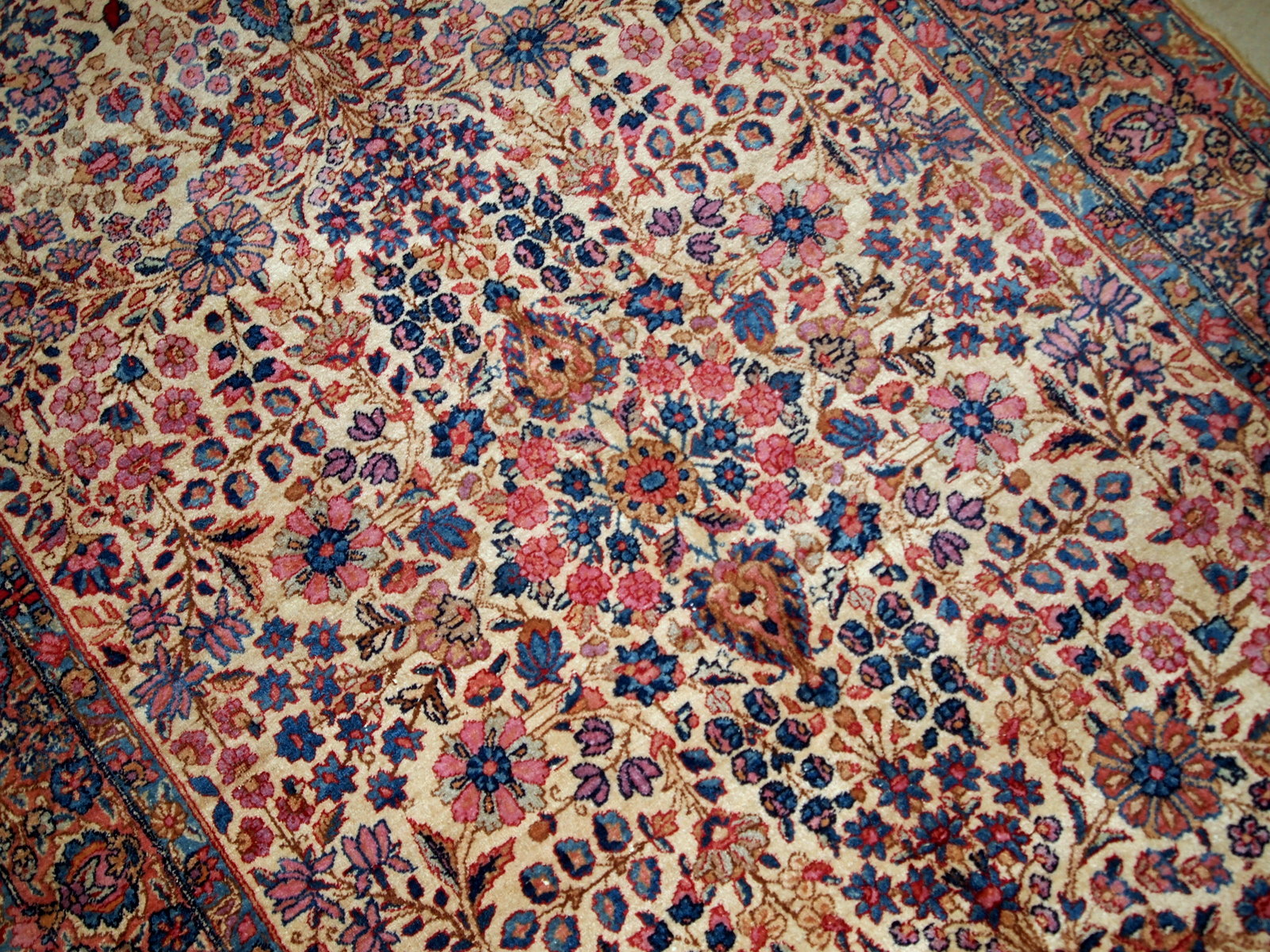 Hand-woven antique Kerman rug in original good condition, from the beginning of 20th century. The rug is in light shades and busy floral design.