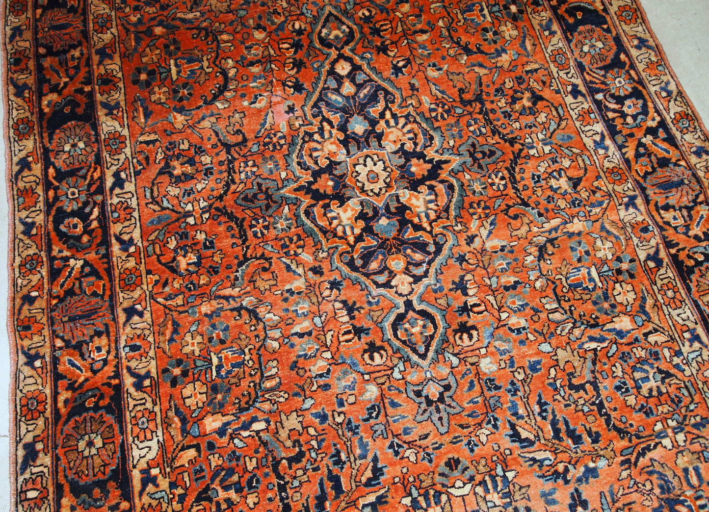 Handmade antique Sarouk rug from the beginning of 20th century. The rug is in original good condition made in red wool.
