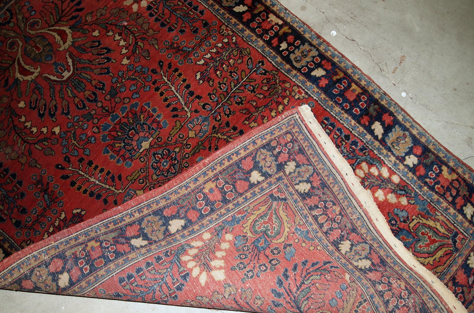Handmade antique Sarouk rug in red color. The rug is from the beginning of 20th century in original good condition.