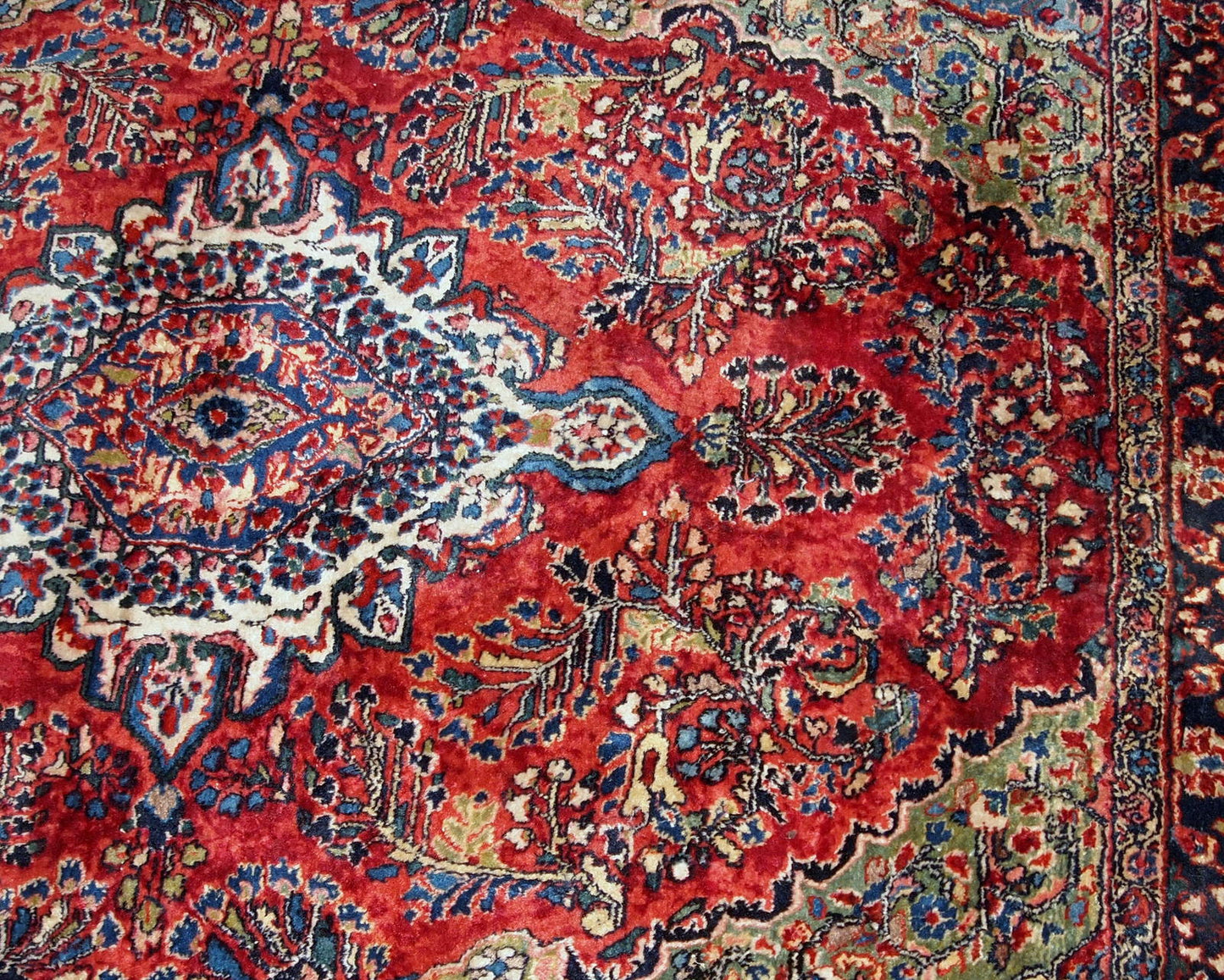 Handmade antique Sarouk rug in red color. The rug is from the beginning of 20th century in original good condition.