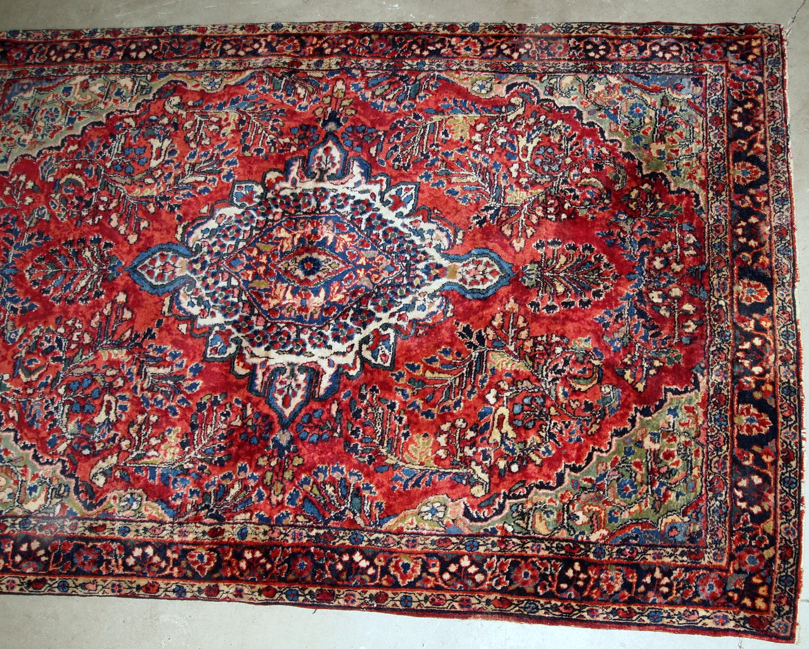 Handmade antique Sarouk rug in red color. The rug is from the beginning of 20th century in original good condition.
