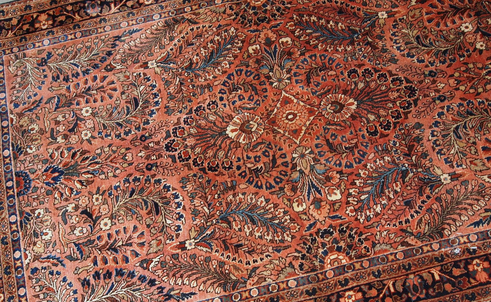 Handmade antique Persian Sarouk rug in original good condition. The rug is from the beginning of 20th century made in red wool.