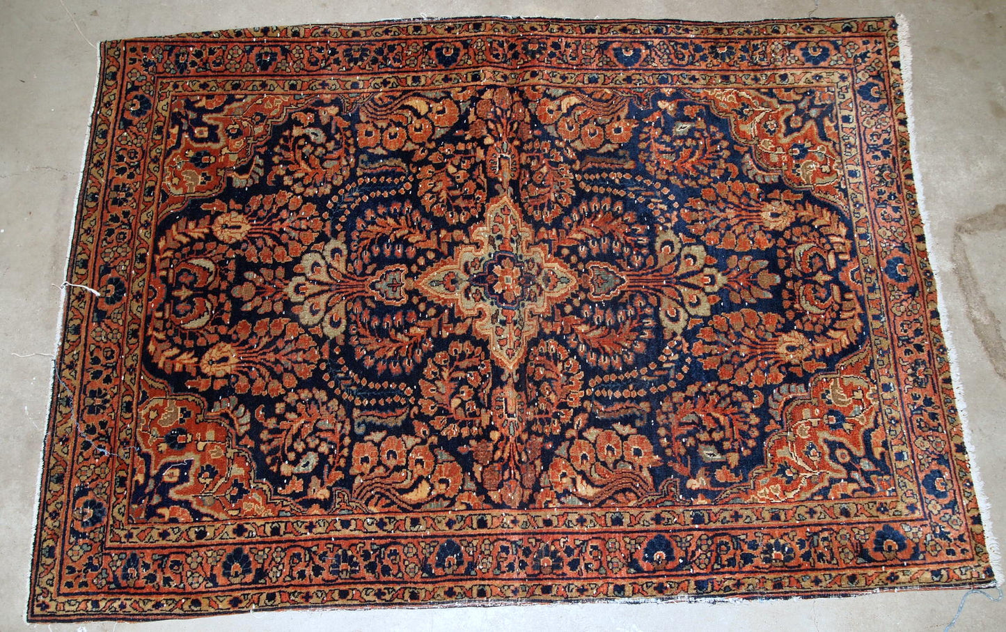 Handmade antique Persian Sarouk rug in original condition, it has some signs of age. The rug is from the beginning of 20th century made in red wool.
