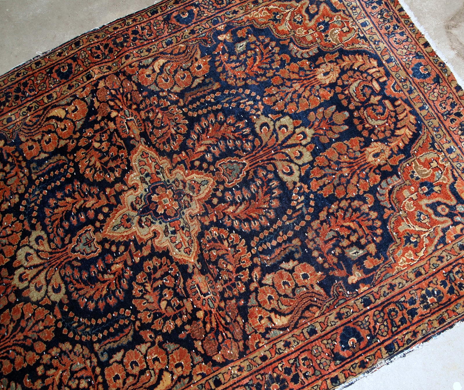 Handmade antique Persian Sarouk rug in original condition, it has some signs of age. The rug is from the beginning of 20th century made in red wool.