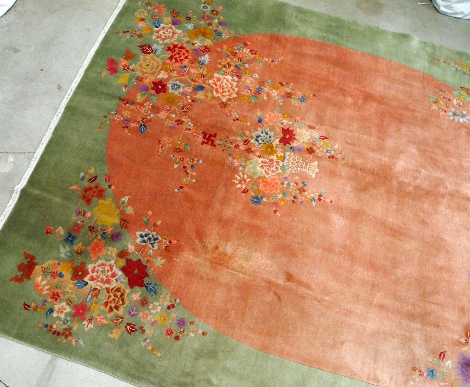 Handmade antique Art Deco Chinese rug in orange and green colors. The rug is from the end of 20th century in original good condition. The rug has a symbol of Indian swastikas'.