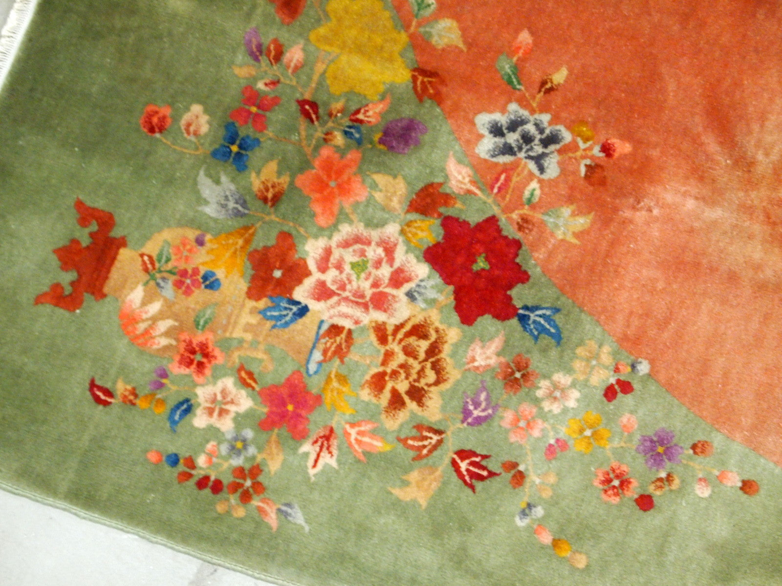 Handmade antique Art Deco Chinese rug in orange and green colors. The rug is from the end of 20th century in original good condition. The rug has a symbol of Indian swastikas'.