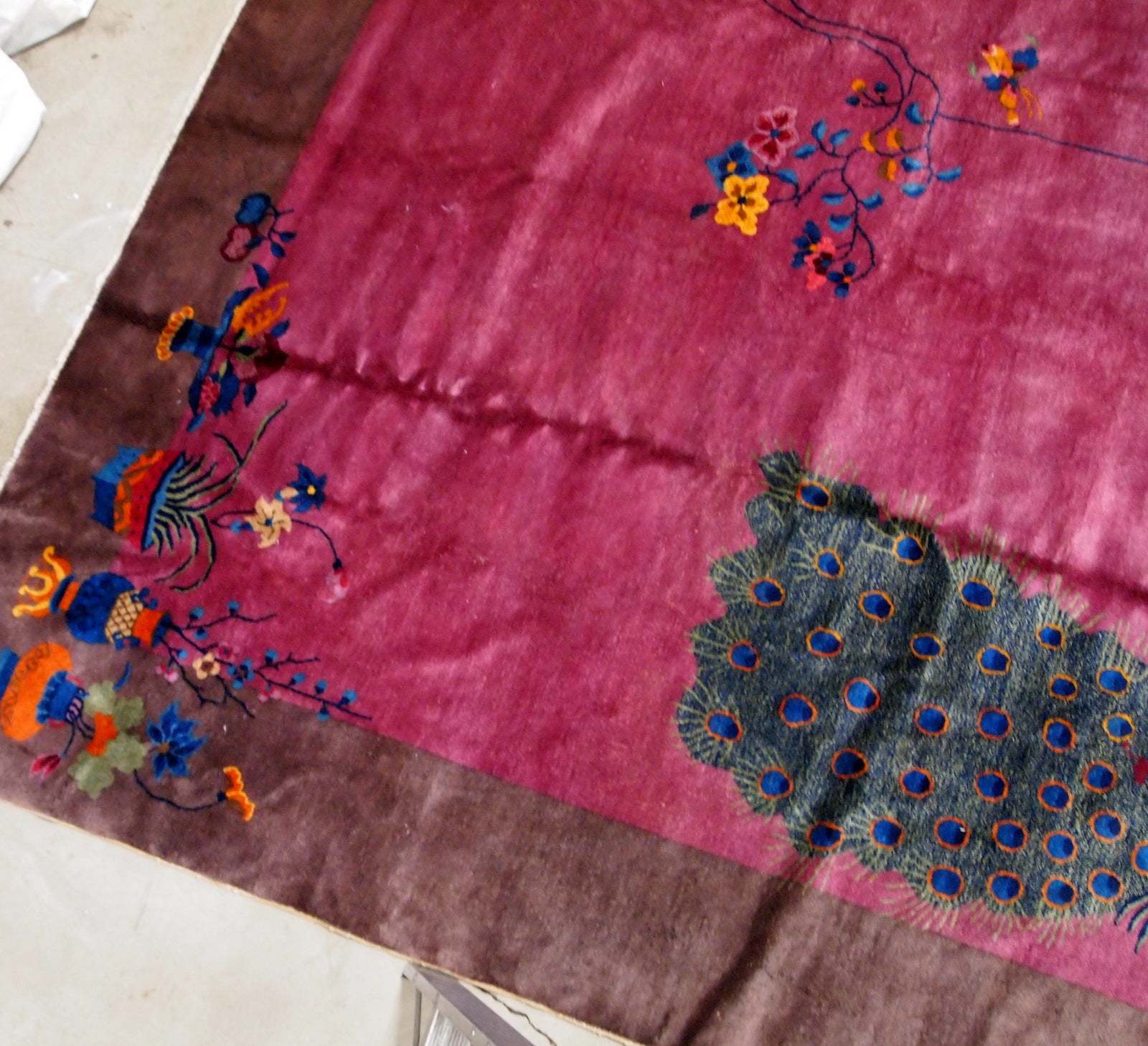 Handmade antique Art Deco Chinese rug in ruby and burgundy shades. The rug is from the beginning of 20th century in original good condition. It has some floral accent with large peacock on it.