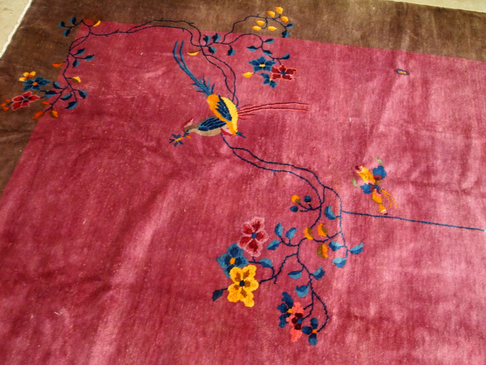 Handmade antique Art Deco Chinese rug in ruby and burgundy shades. The rug is from the beginning of 20th century in original good condition. It has some floral accent with large peacock on it.