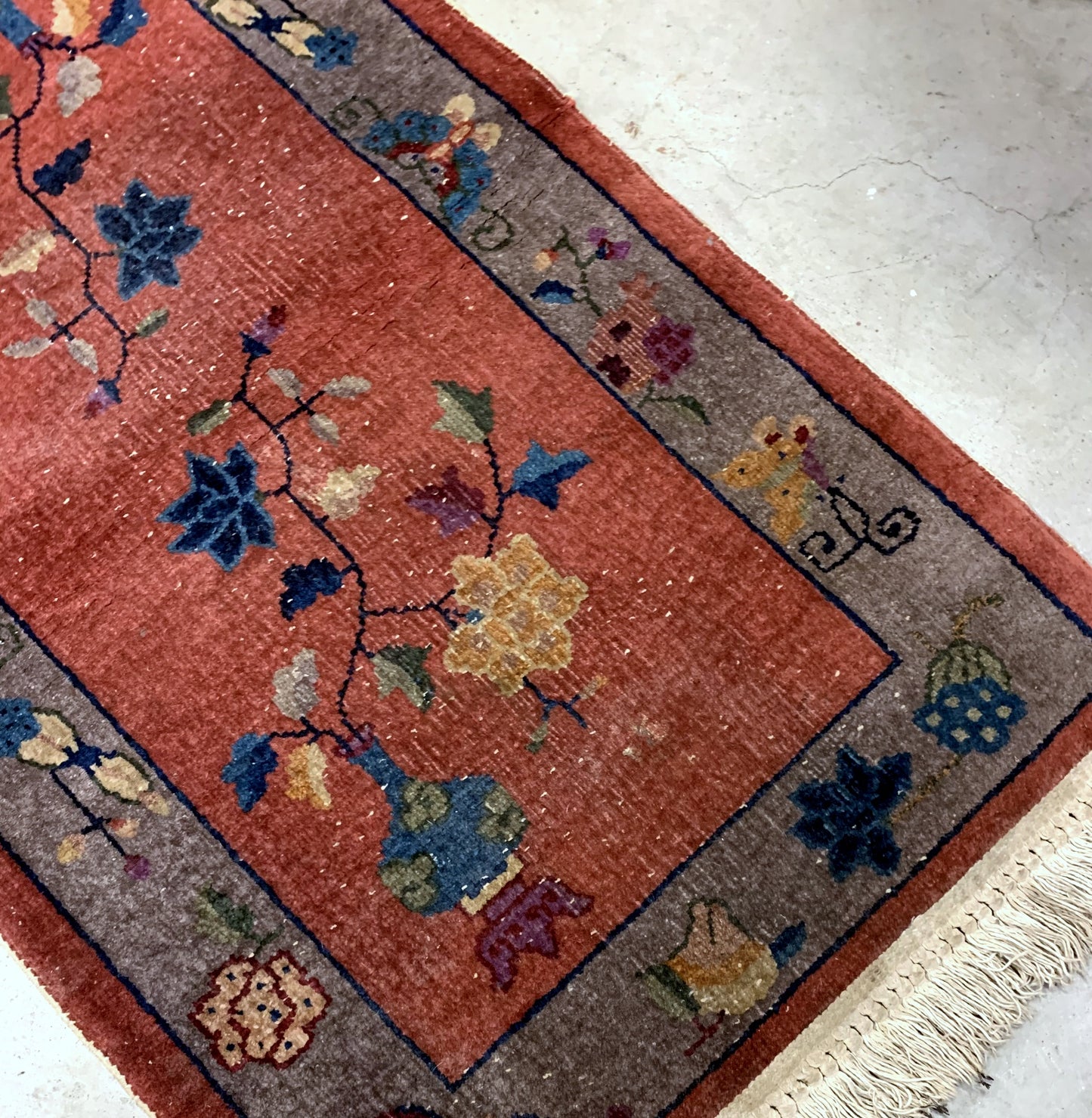 Handmade antique Art Deco Chinese rug in red shade with greyish border. The rug has traditional floral Art Deco design. It is from the beginning of 20th century in original condition, it has some low pile.