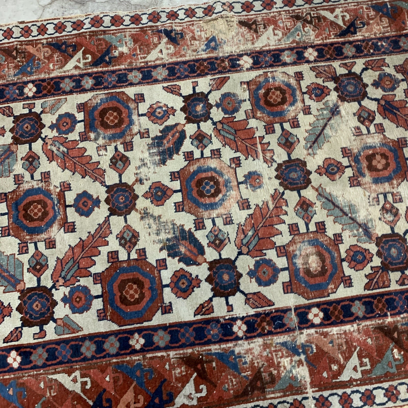 Very old handmade antique North-West Persian rug in white and red background colors. The rug is from the beginning of 19th century in distressed condition.  