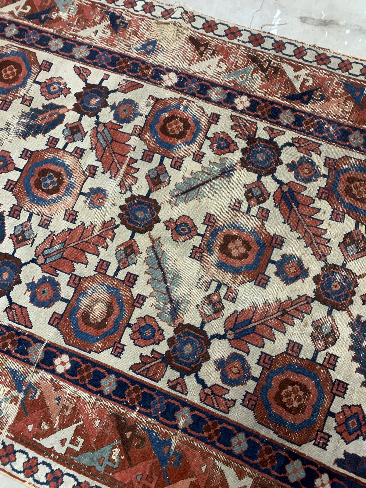 Very old handmade antique North-West Persian rug in white and red background colors. The rug is from the beginning of 19th century in distressed condition.  