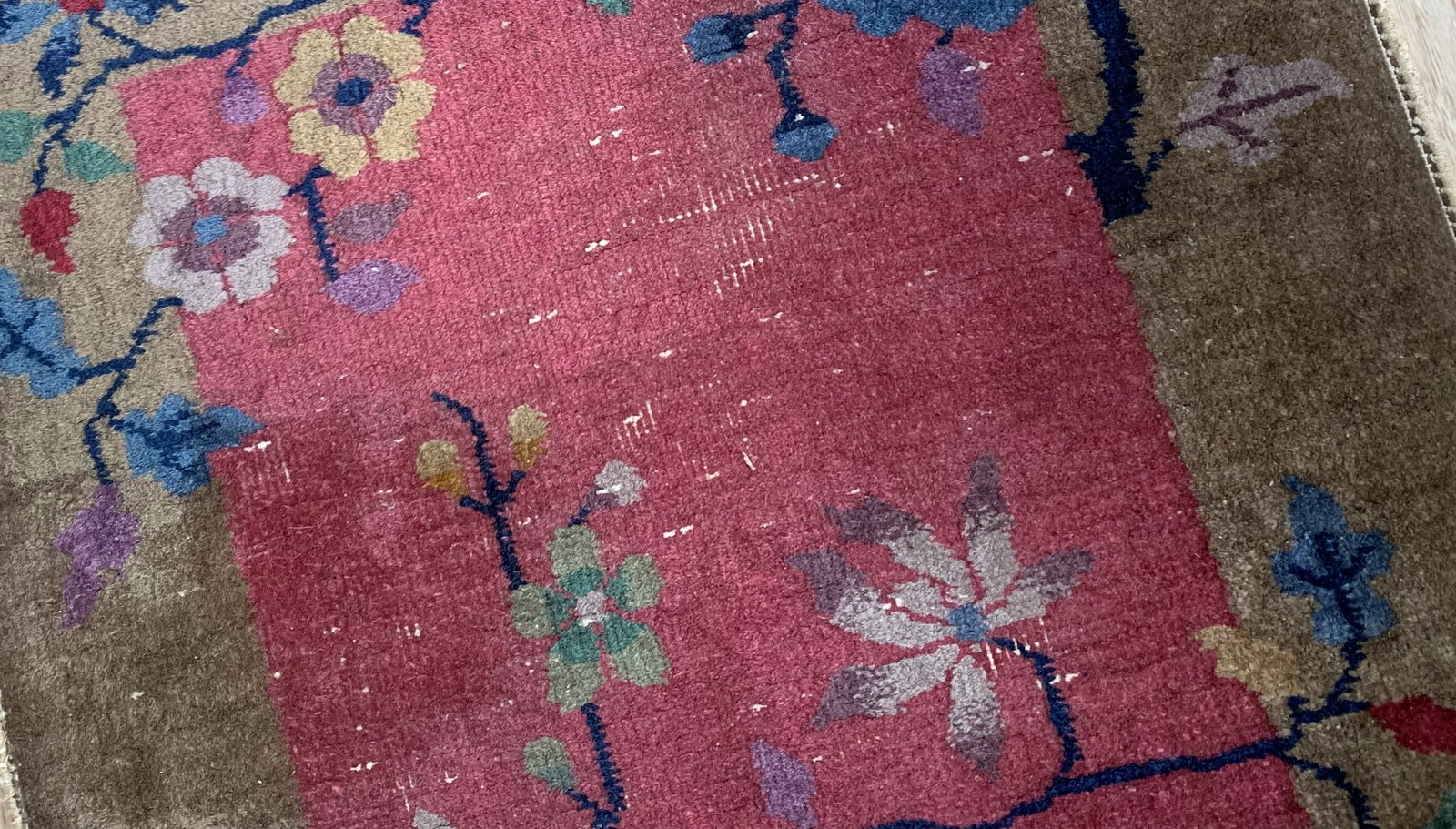 Detailed view of handmade woolen rug from China with fuchsia, blue, olive, purple, and yellow colors.