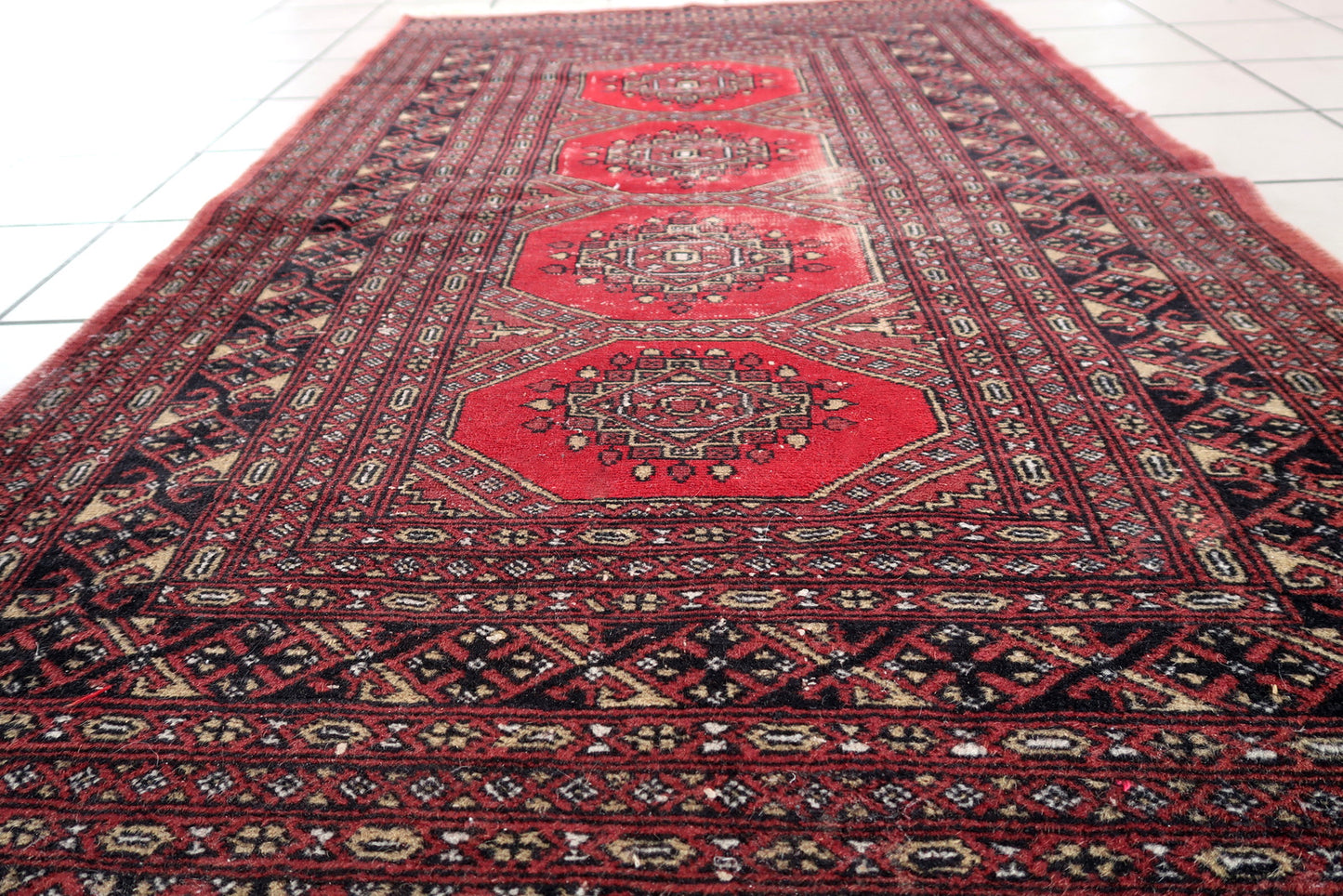 Handmade vintage Uzbek Bukhara rug in classic design. The rug is from the end of 20th century in distressed condition.