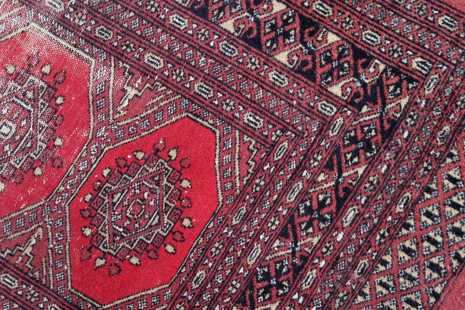 Handmade vintage Uzbek Bukhara rug in classic design. The rug is from the end of 20th century in distressed condition.