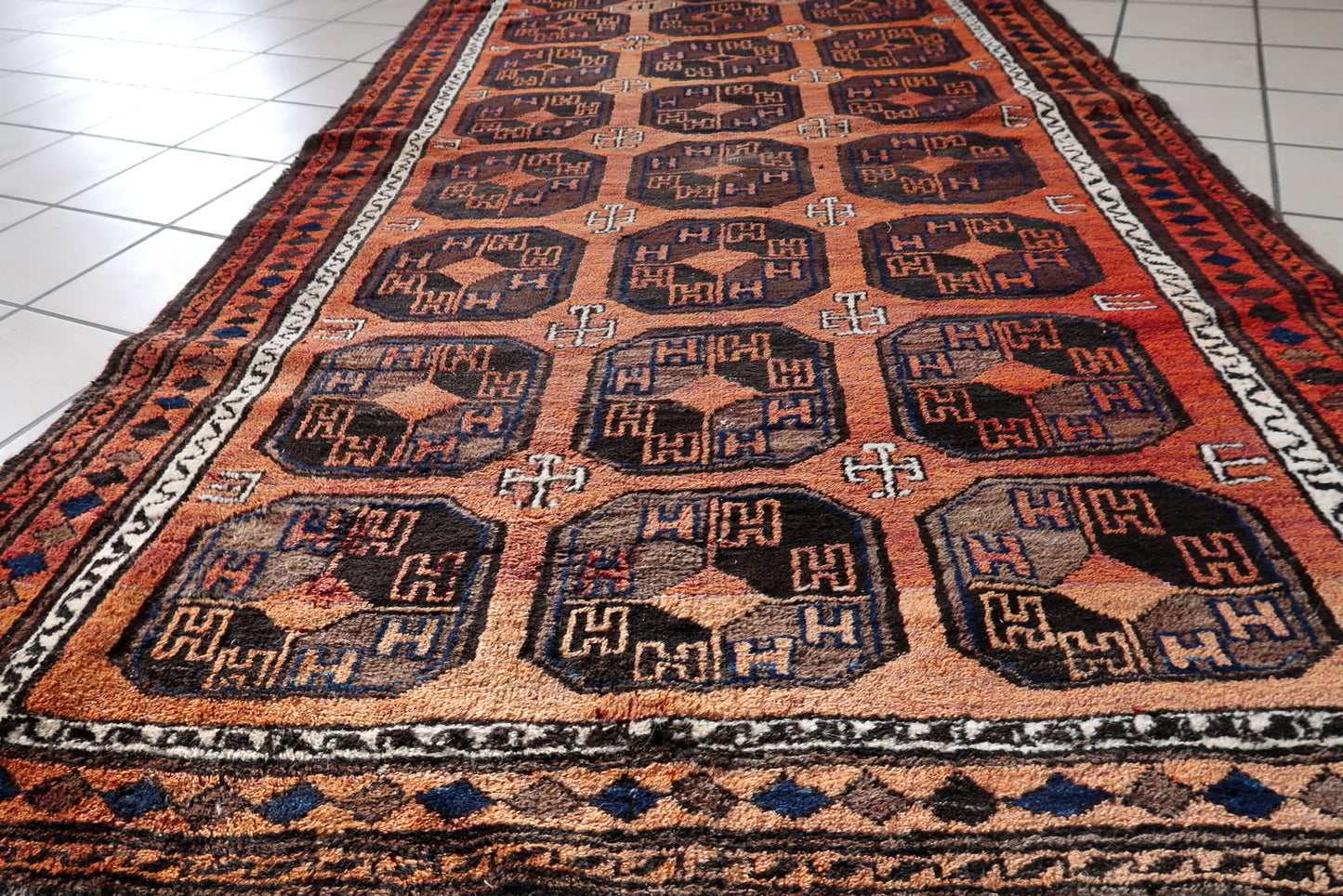 Handmade antique Afghan Baluch rug in repeating pattern. The rug is from the beginning of 20th century in original condition, it has some low pile.