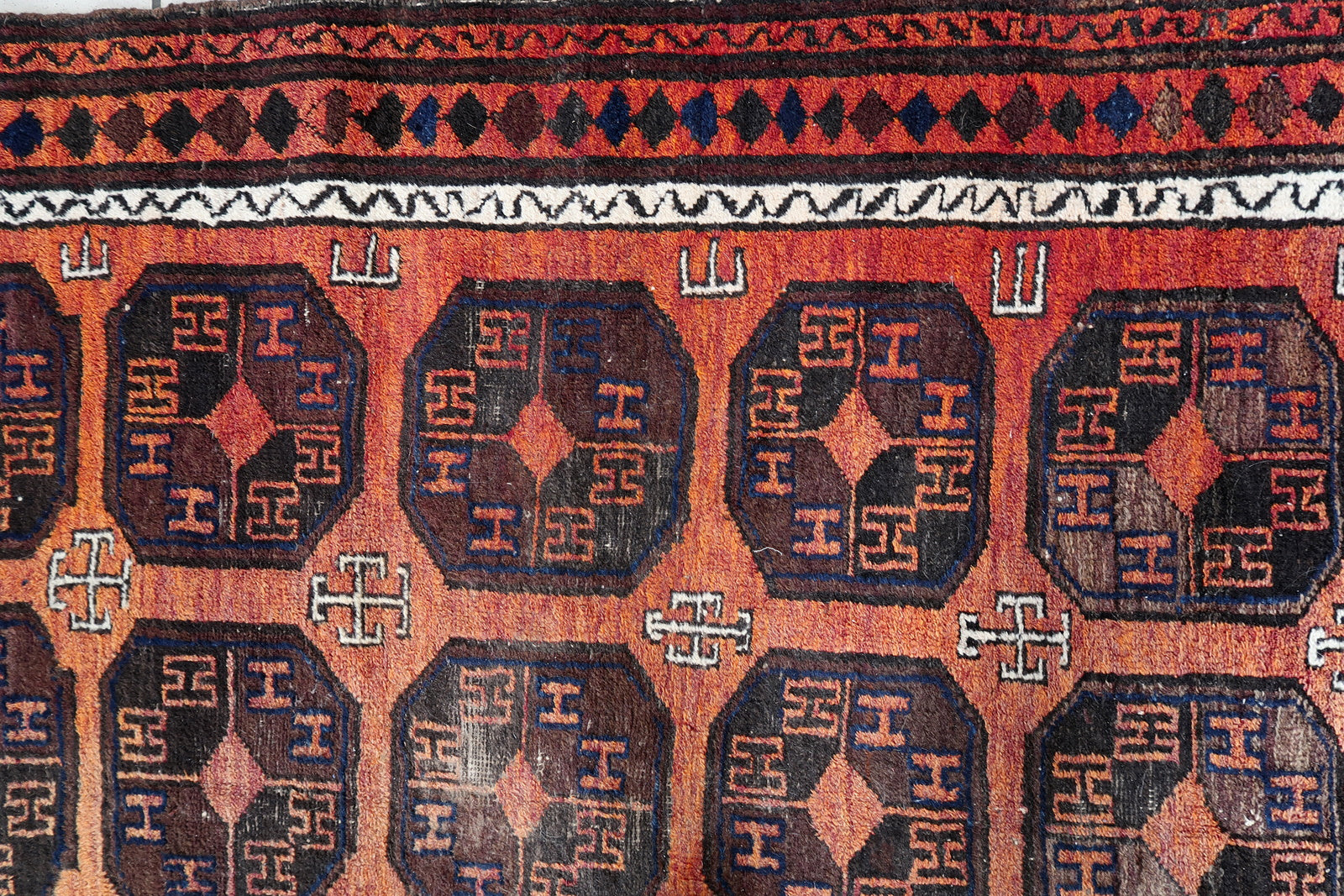 Handmade antique Afghan Baluch rug in repeating pattern. The rug is from the beginning of 20th century in original condition, it has some low pile.