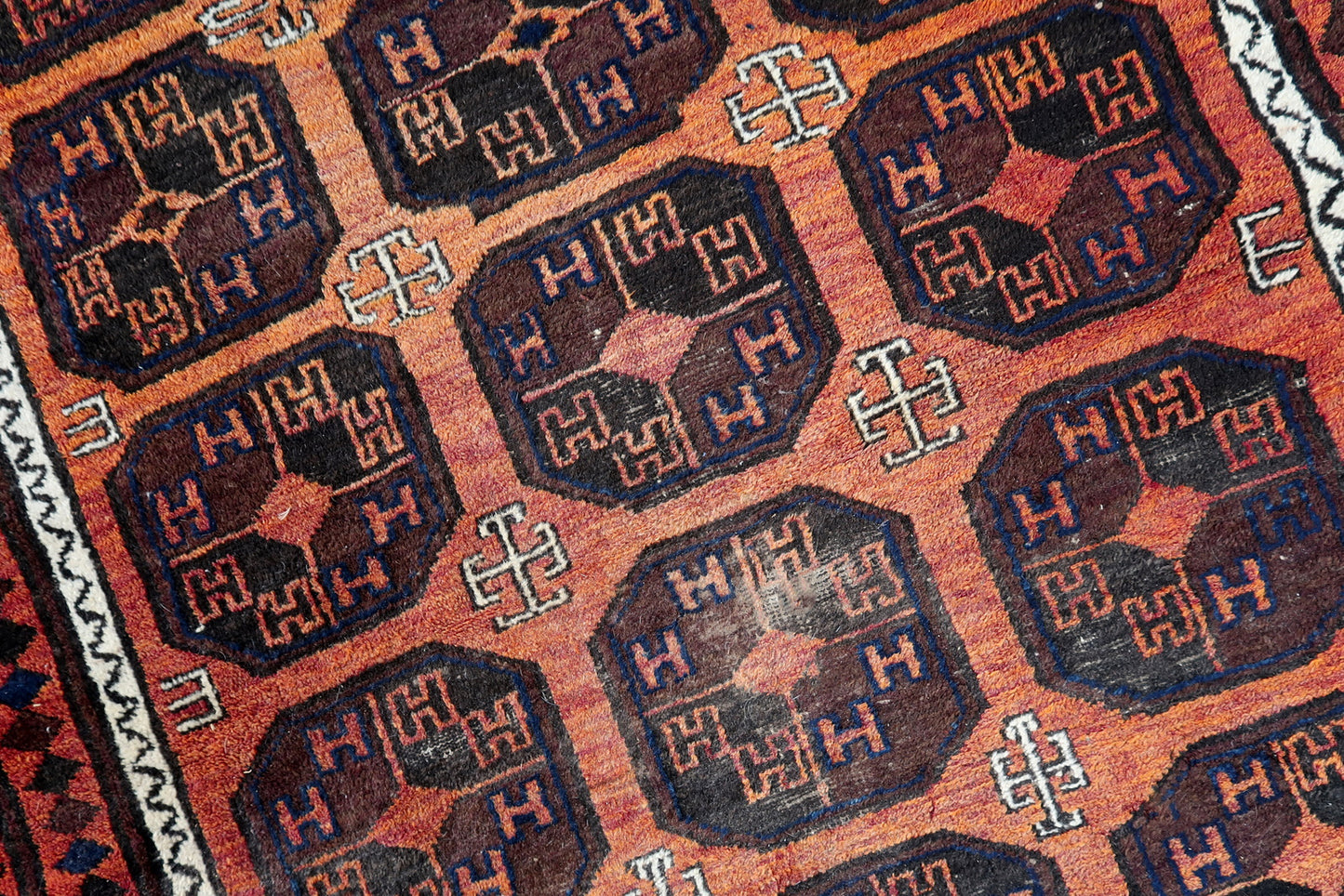 Handmade antique Afghan Baluch rug in repeating pattern. The rug is from the beginning of 20th century in original condition, it has some low pile.