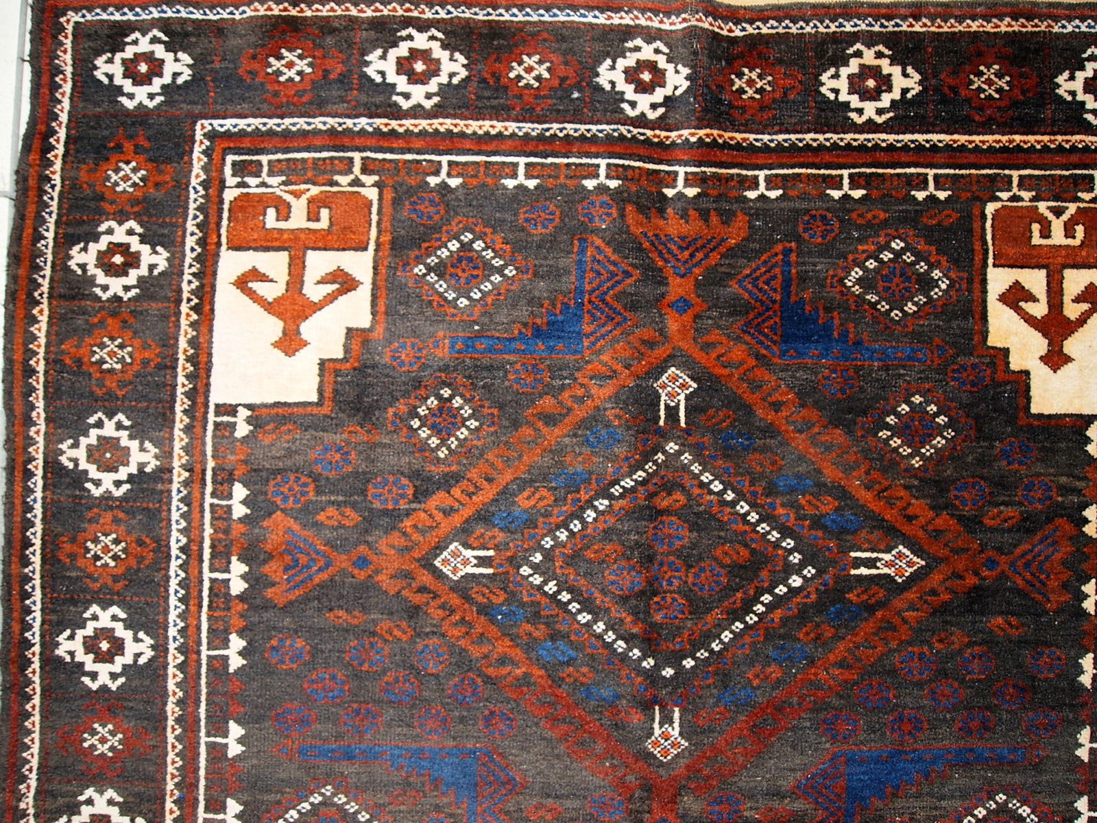 Detailed shot of white patterns and figures on the vintage Afghan rug.