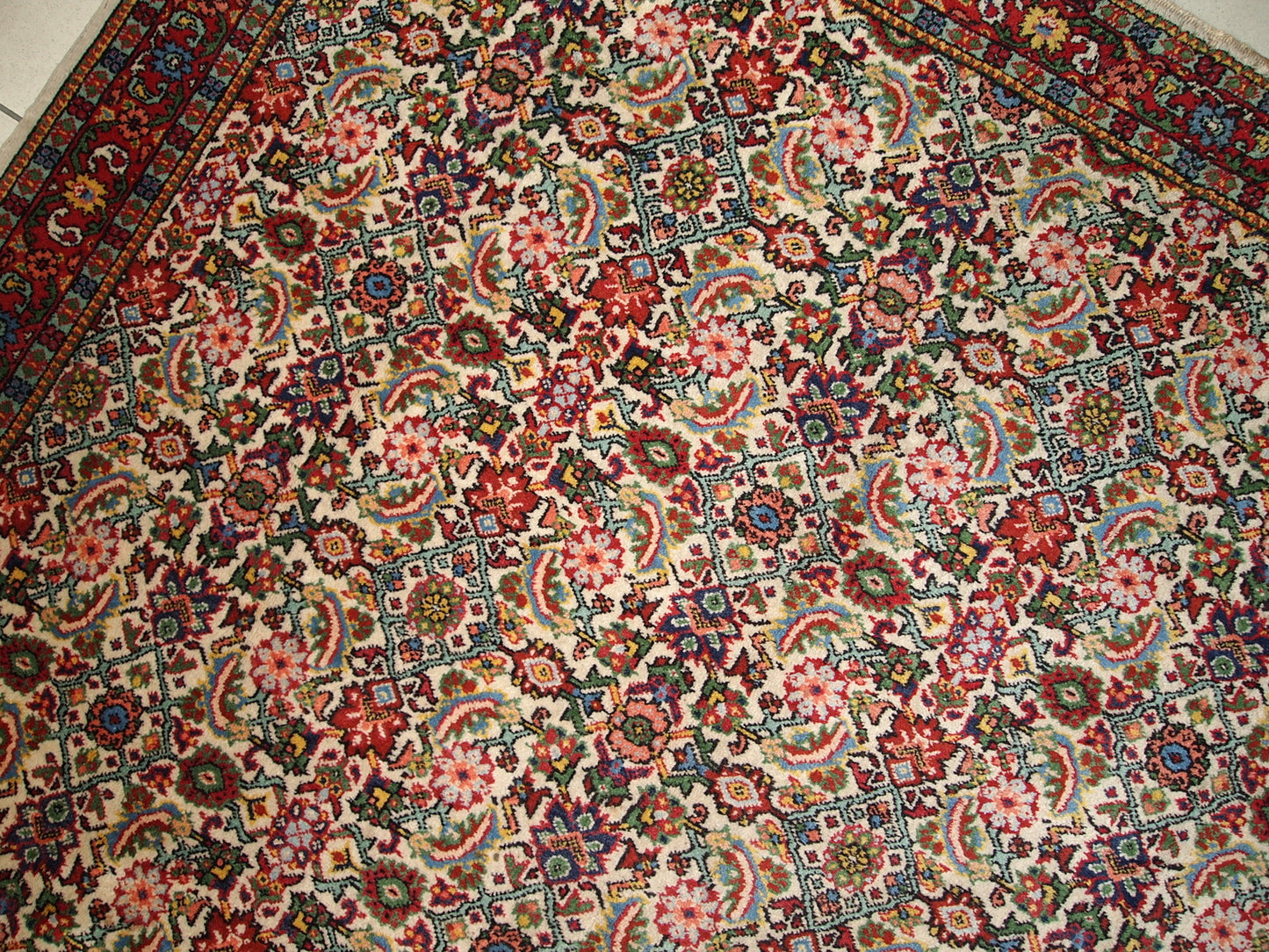 Antique rug with vibrant red, pink, green, and blue colors