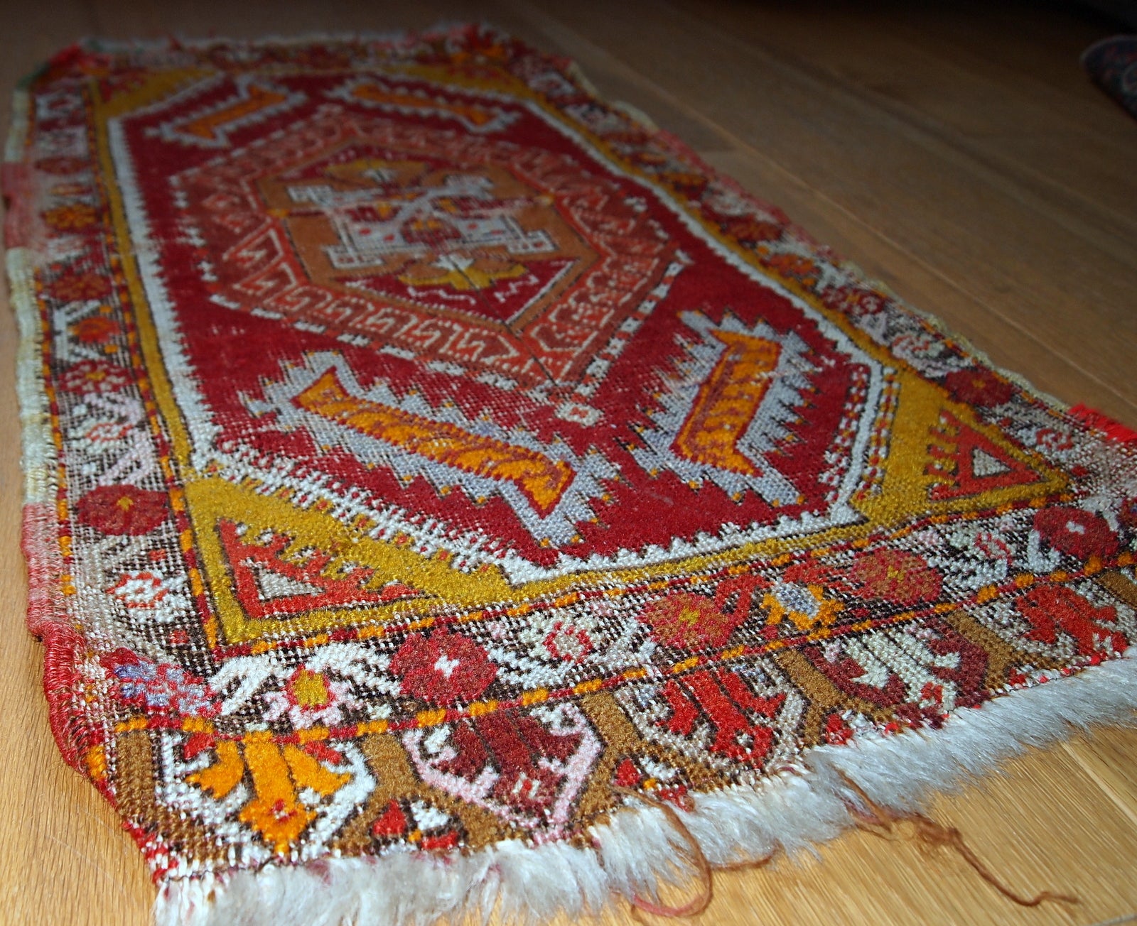 Antique Turkish Yastik rug in distressed condition. The rug made in red color with some accents of gold, orange and olive brown shades. 