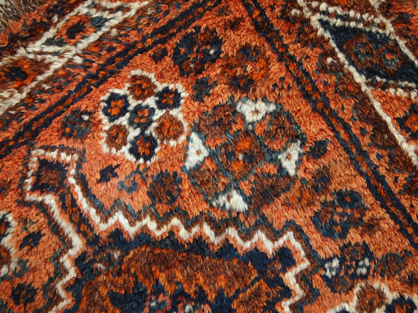 Antique collectible Persian Shiraz rug in original good condition. The rug is in rust shade with navy blue and white details. 